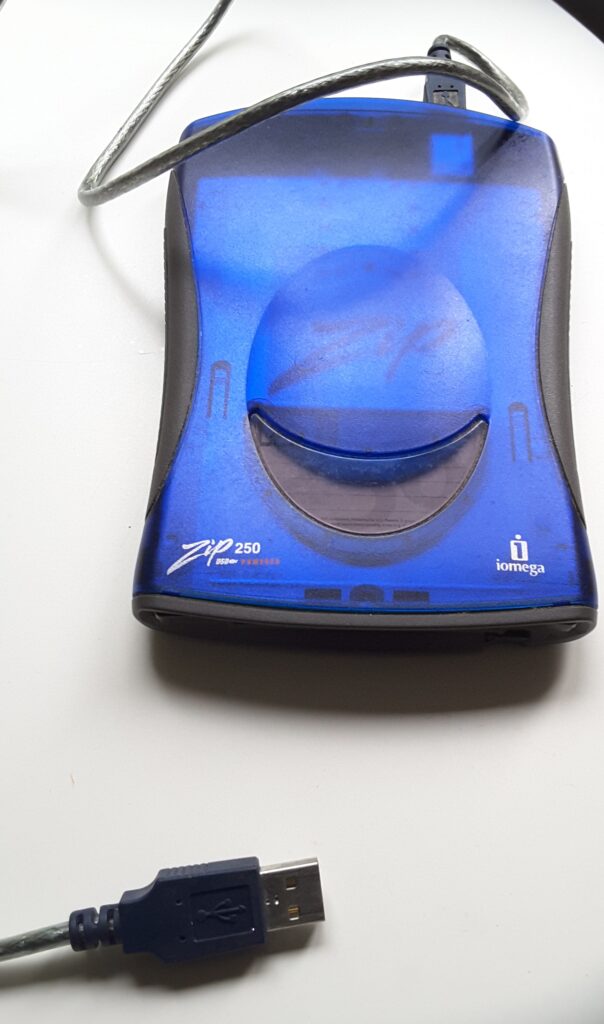 Photographie d'un lecteur ZIP Iomega 250. L'appareil est bleu, assez élégant, et dispose d'une unique connectique USB.