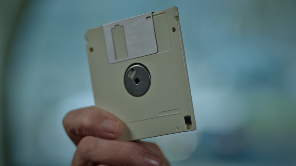 Capture d'écran du film La découverte de la chouette d'or. On y voit un gros plan de la disquette, probablement toujours tenue par M. Becker.